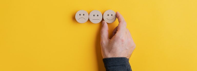 Bewertung Male hand choosing a smiling face option from the row of three choices
